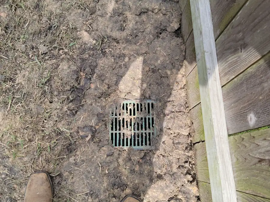 Open dirt trench running along a wooden privacy fence